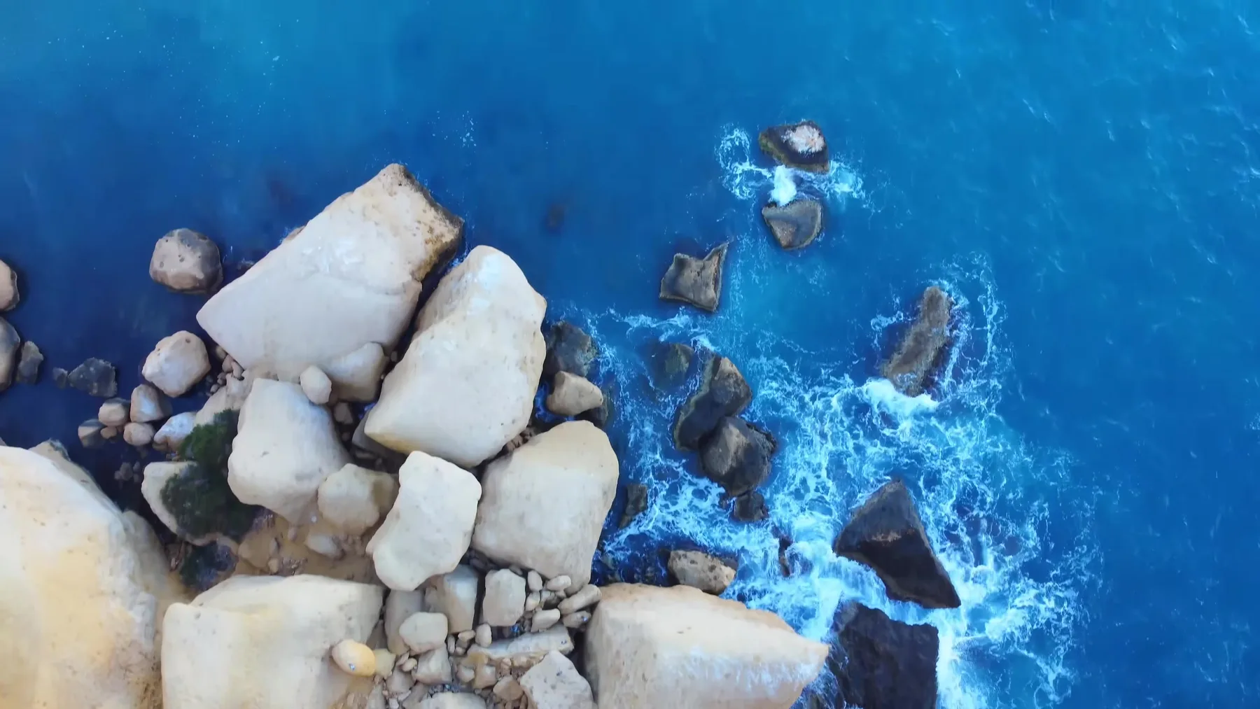 Rocas blancas sobre agua azul intenso en la costa de Terreros